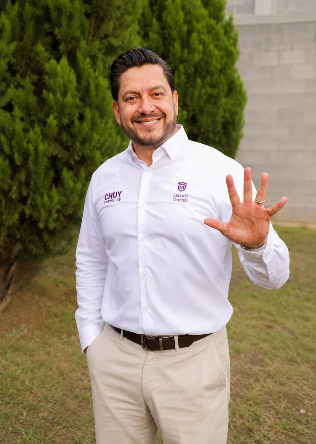 Chuy Carrilles con camisa de Escudo Vecinal mostrando la palma abierta con los cinco dedos, en alusión a los cinco vecinos cercanos.